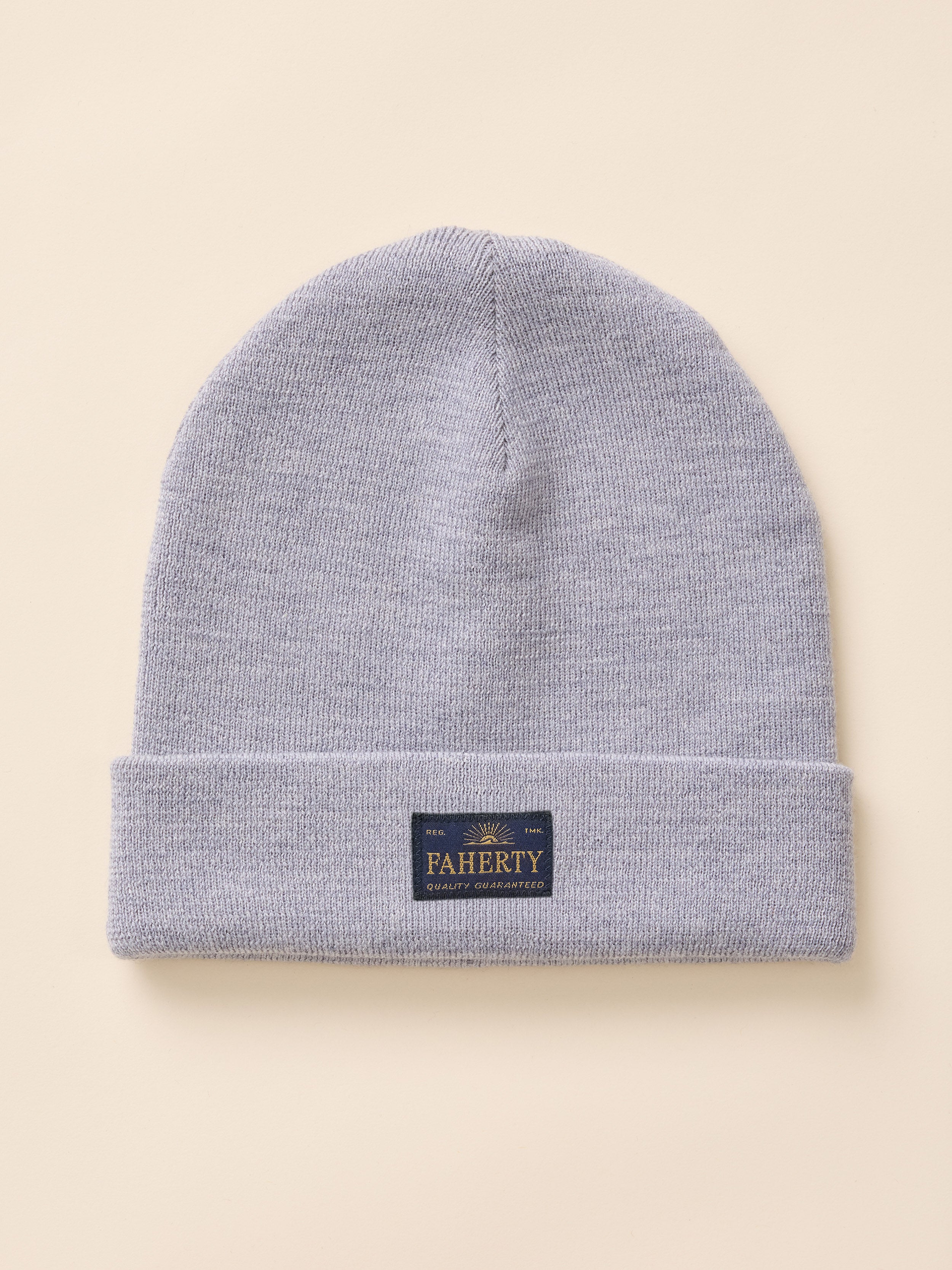 A light gray heather knit beanie hat with a folded cuff, featuring a small dark navy brand patch that reads 'PAHERTY' in gold lettering, set against a solid beige background.