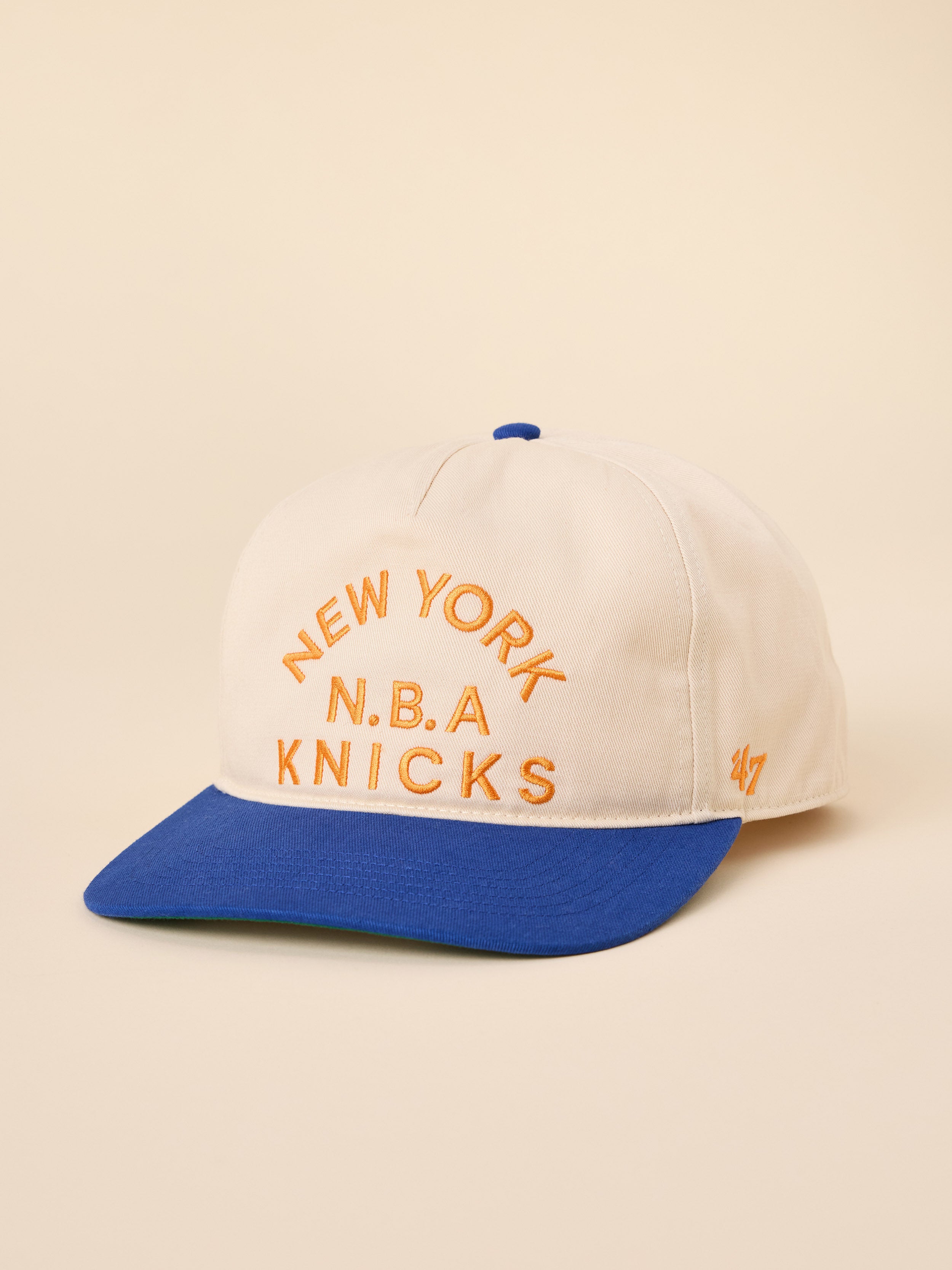 A beige and blue NY Knicks hat