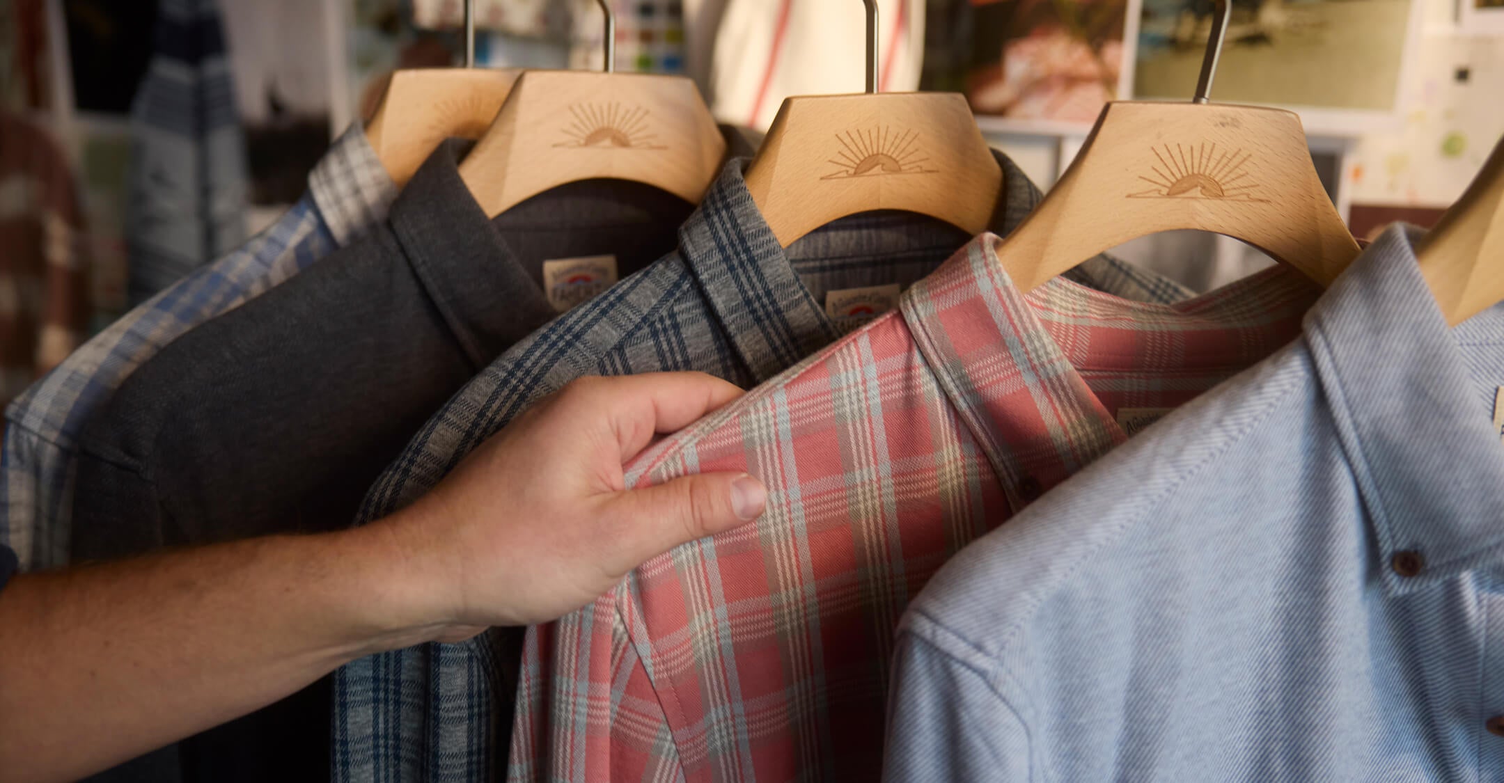A rack of Coastline Knit Shirts with a hand selecting one of them
