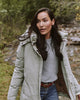 A woman in the woods wearing the Faherty Brand chalet puffer. 