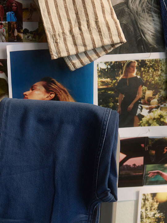 A pair of stretch terry pants draped over a chair in front of a moodboard of lifestyle images and fabric swatches