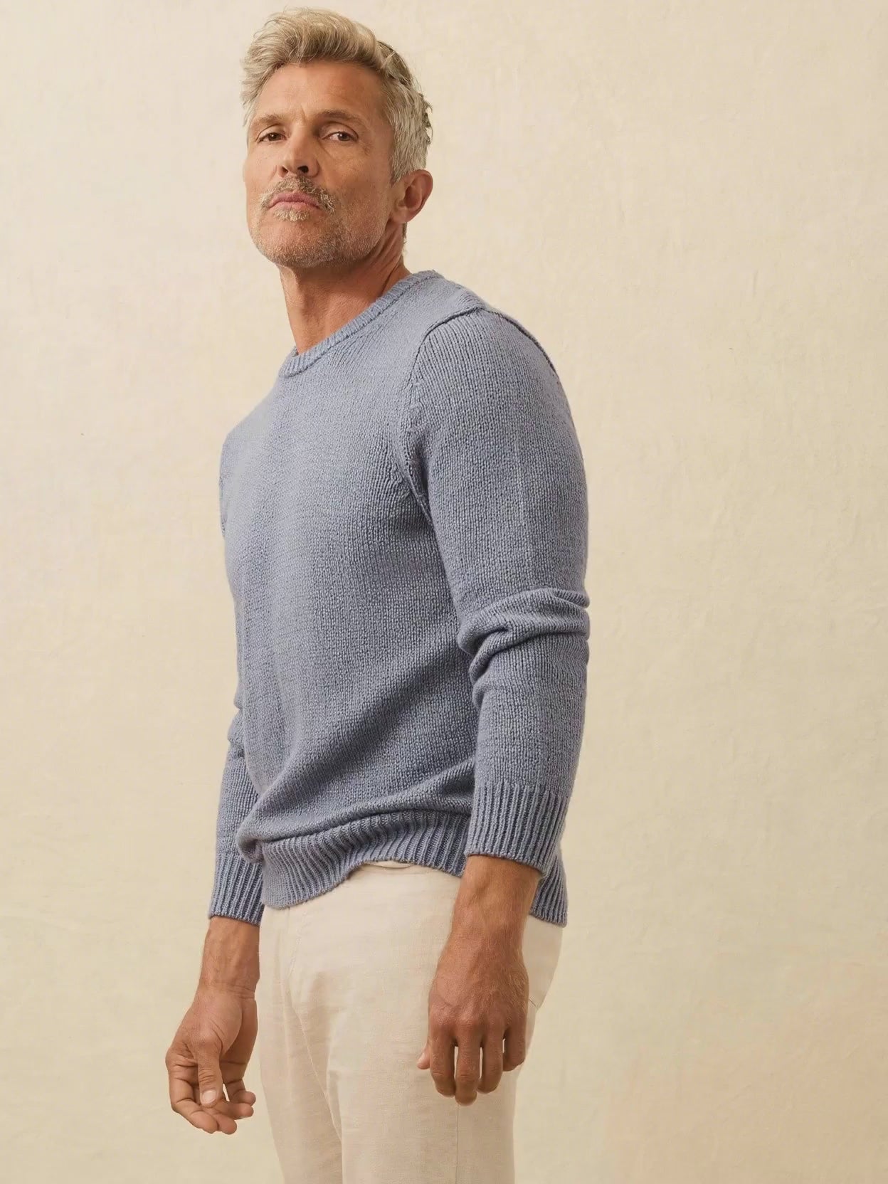 Man wearing a blue sweater against a beige background
