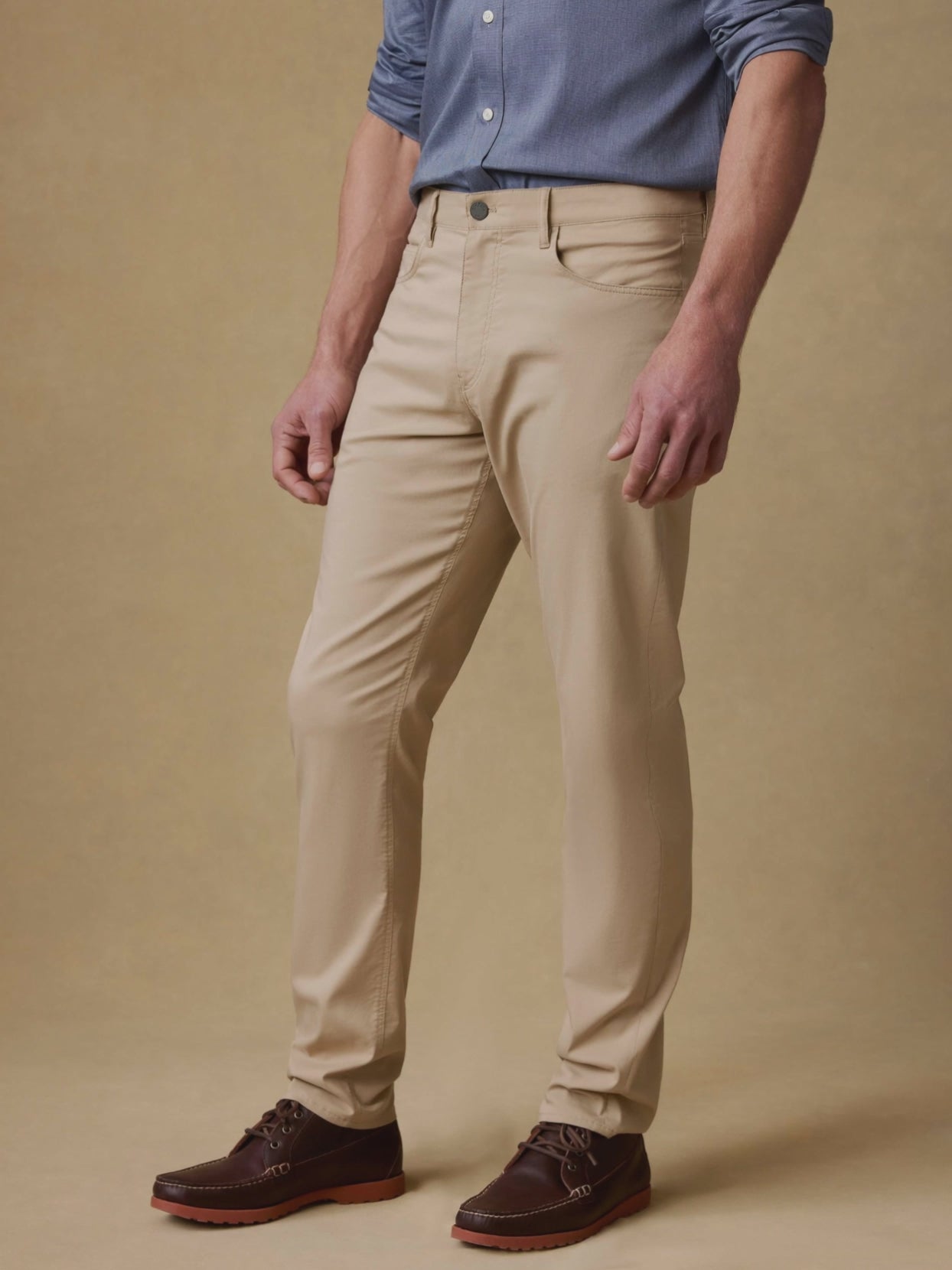 Video of man wearing beige pants with blue long sleeve button up shirt against a beige background