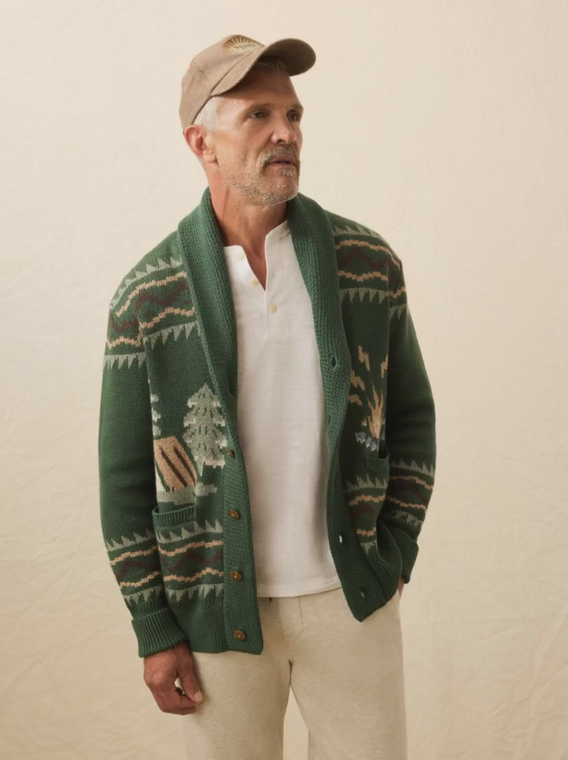 Man wearing a green button cardigan with all around graphic against the beige background