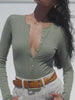 Video of a woman wearing an olive green henley with beige pants against a white background