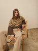 Woman wearing a brown and yellow fairisle sweater against a beige background