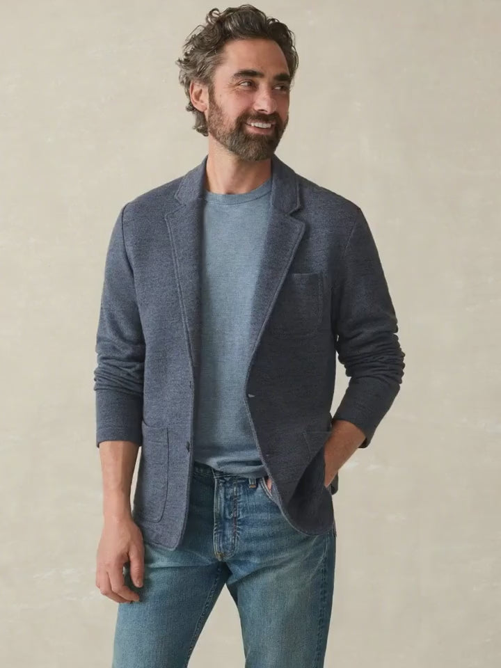 Man wearing a dark navy blazer over a blue shirt against a beige background