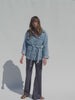 Video of a woman wearing a denim safari jacket and navy and white striped knitted pants against a white background