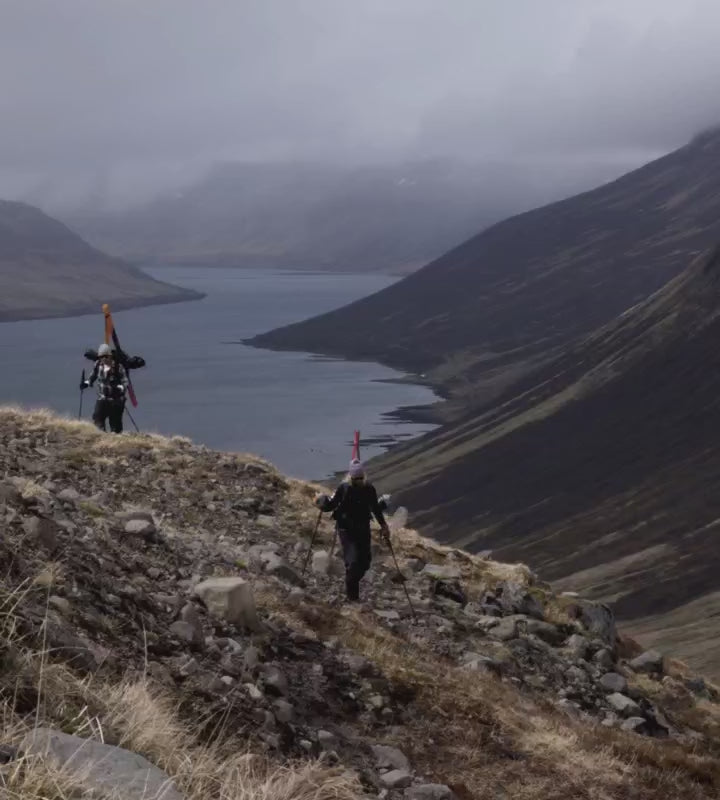 Couple trekking through Icelandic mountains then skiing through the snow