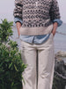 Video of a woman wearing a beige and black fairisle sweater over a chambray shirt and white pants