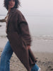 Video of a woman wearing a brown coat over a striped shirt and blue jeans