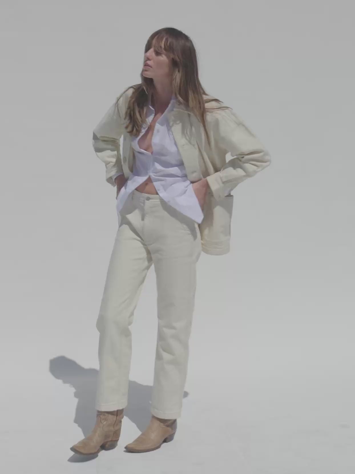 Video of a woman wearing a cream core jacket and matching pants against a beige background