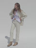 Video of a woman wearing a cream core jacket and matching pants against a beige background