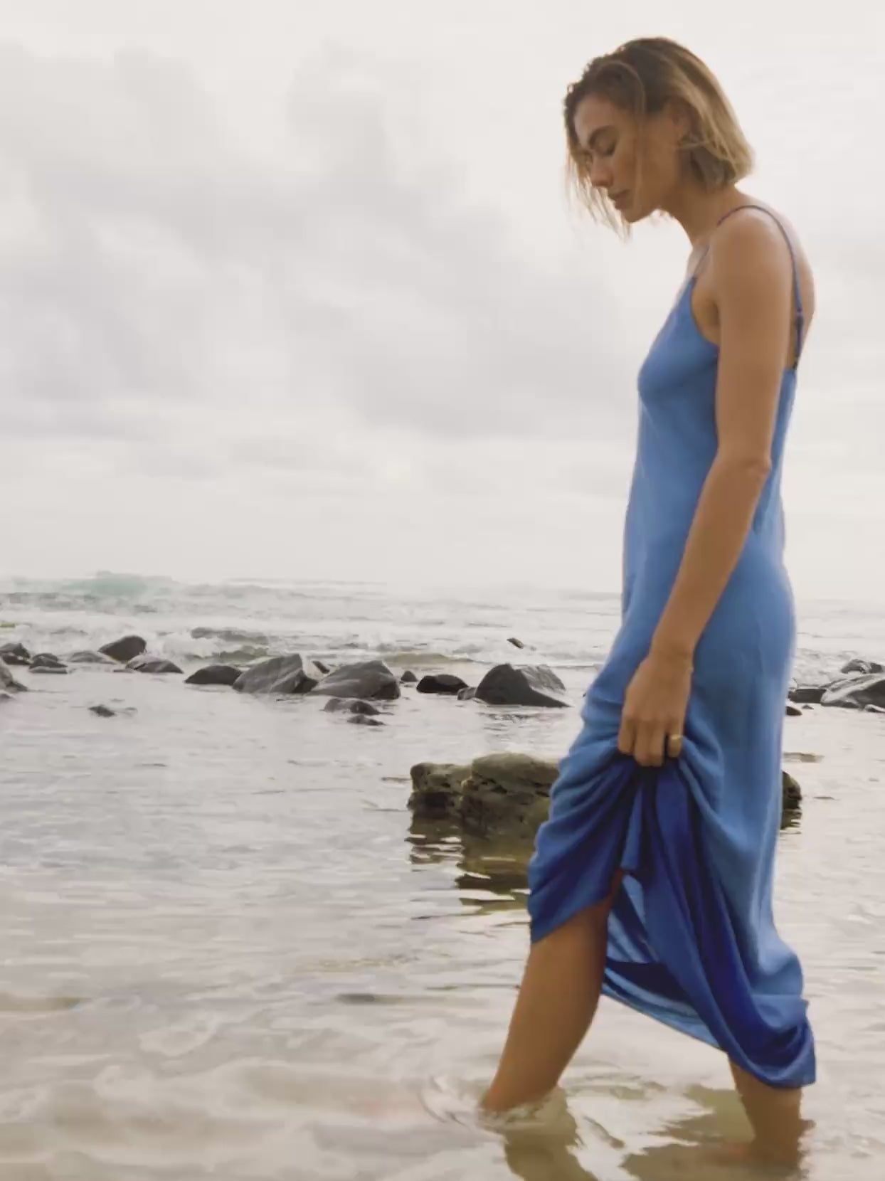 Woman wearing a blue maxi dress walking along the beach