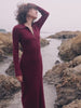 Video of a woman wearing a red maxi dress standing in tidepools