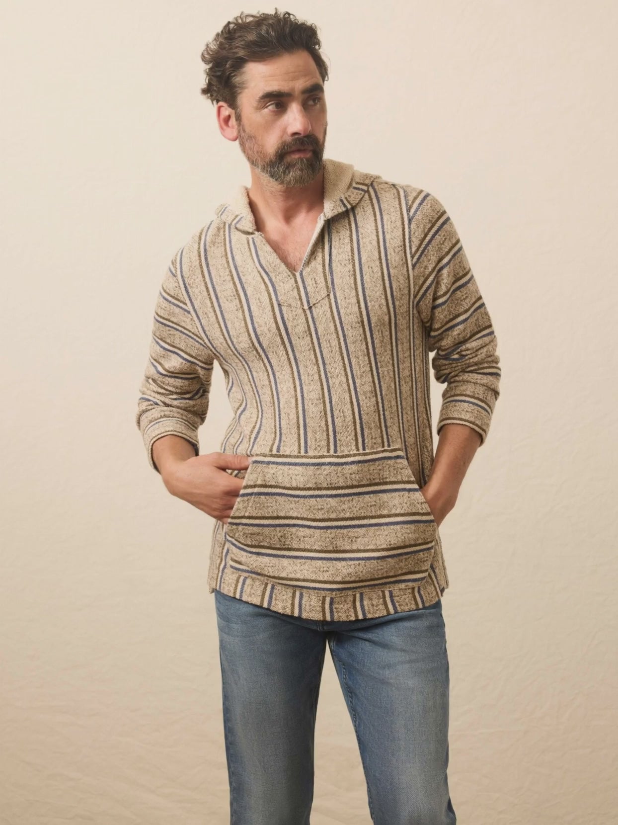 Man wearing a striped hoodie and jeans standing against a plain background